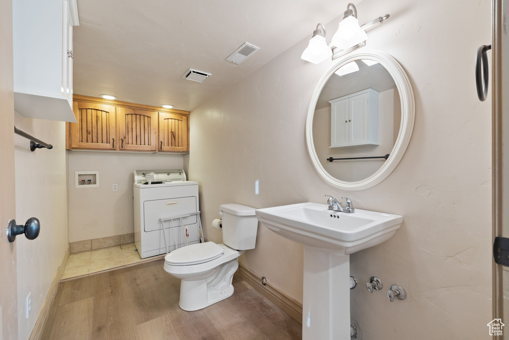 Bathroom featuring toilet, washer / clothes dryer, and hardwood / wood-style flooring