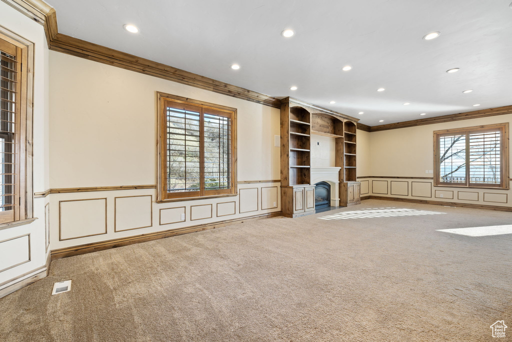 Unfurnished living room with light colored carpet and crown molding