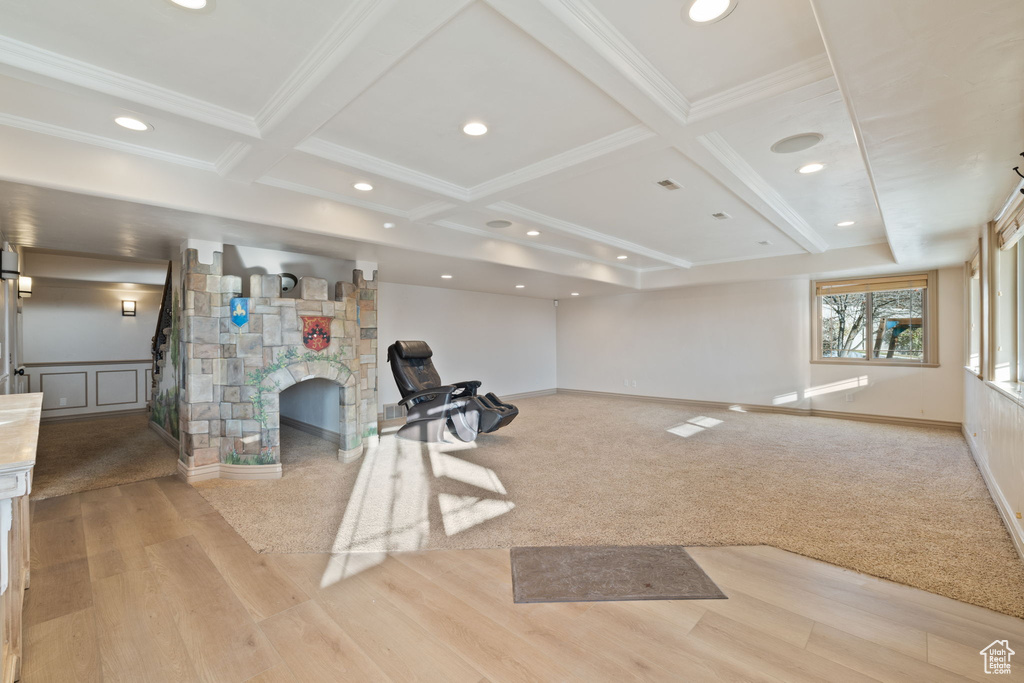 Exercise room with a stone fireplace, light hardwood / wood-style flooring, and coffered ceiling