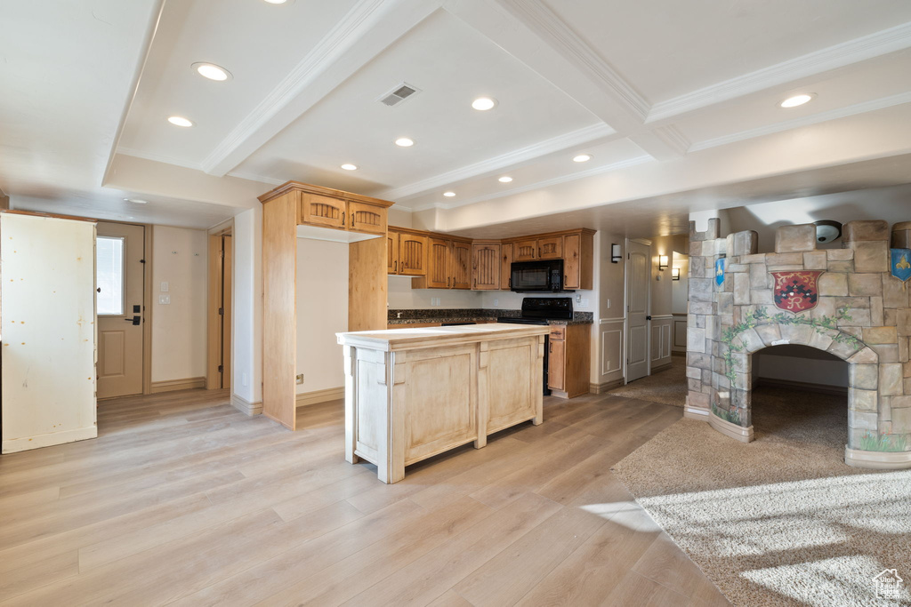 Kitchen with light hardwood / wood-style flooring, range with electric cooktop, a kitchen island, beamed ceiling, and a stone fireplace