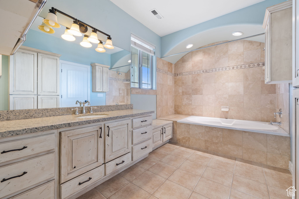 Bathroom featuring tile floors, vanity, and tiled tub