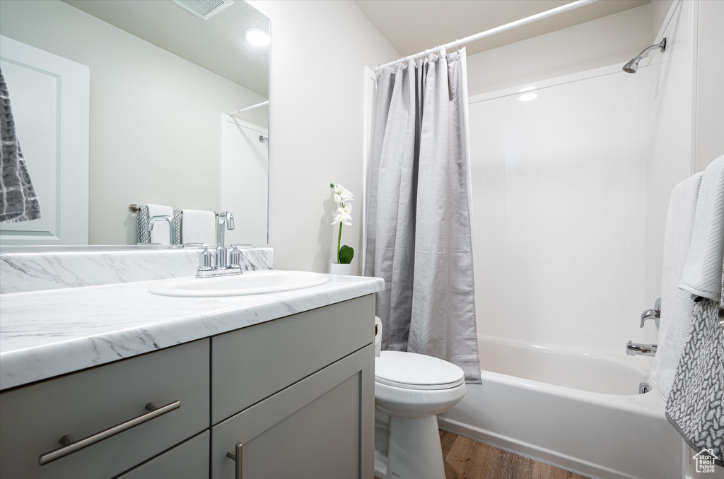 Full bathroom with vanity, toilet, hardwood / wood-style flooring, and shower / bath combo with shower curtain