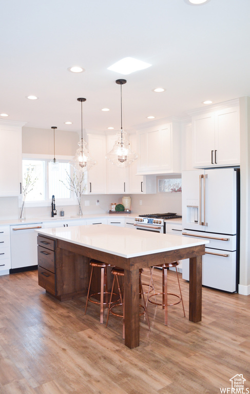 Kitchen featuring a kitchen island, light hardwood / wood-style floors, white appliances, and white cabinetry