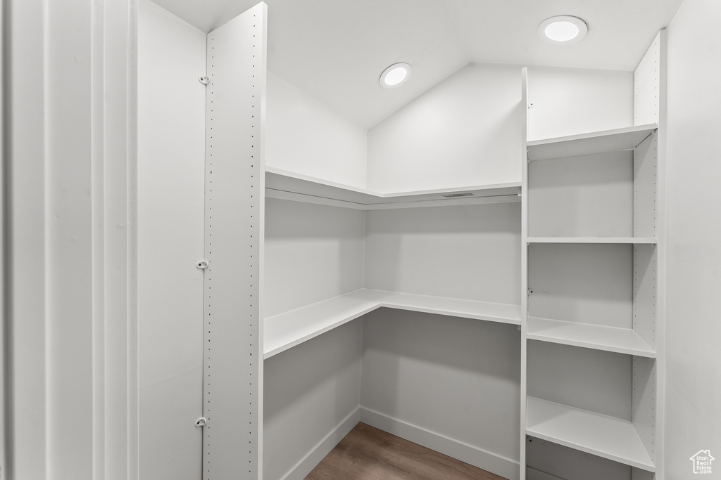 Spacious closet featuring dark hardwood / wood-style flooring and vaulted ceiling