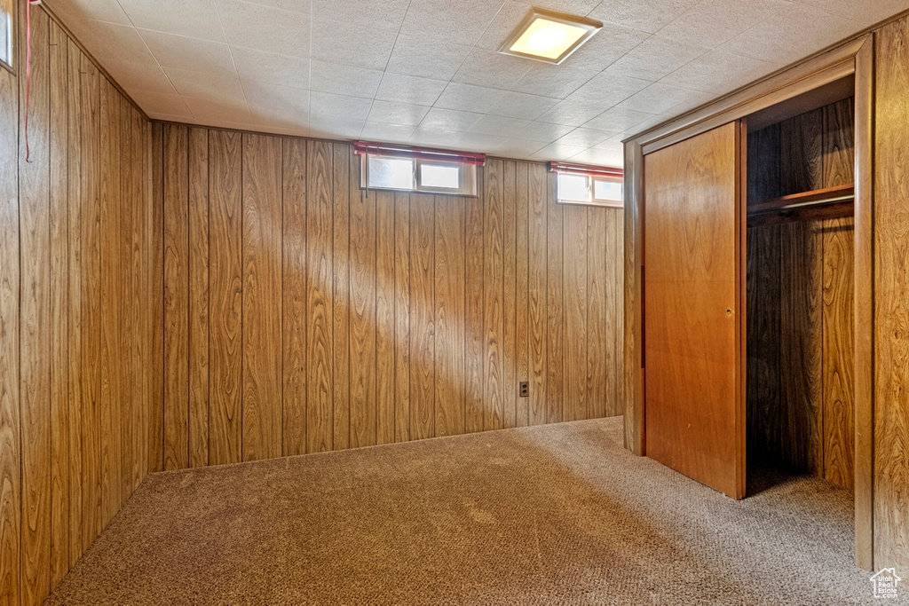 Unfurnished bedroom featuring wood walls, a closet, and carpet floors