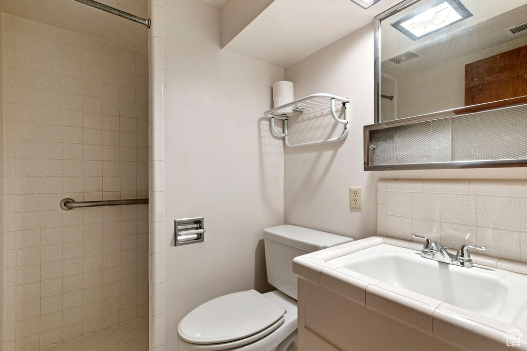 Bathroom with backsplash, tile walls, vanity, and toilet