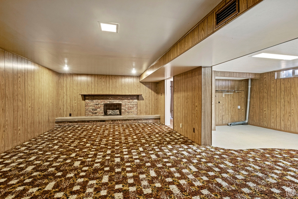 Basement featuring wood walls, light carpet, and a fireplace