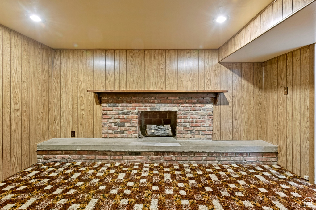 Unfurnished living room featuring a brick fireplace and wood walls