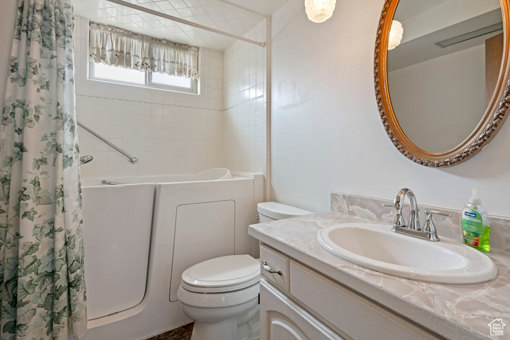 Full bathroom with vanity with extensive cabinet space, shower / bathtub combination with curtain, and toilet