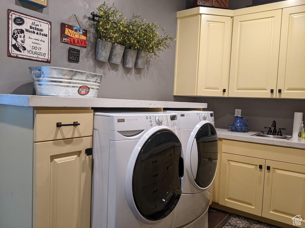 Laundry room with cabinets, sink, washing machine and dryer, and dark tile flooring