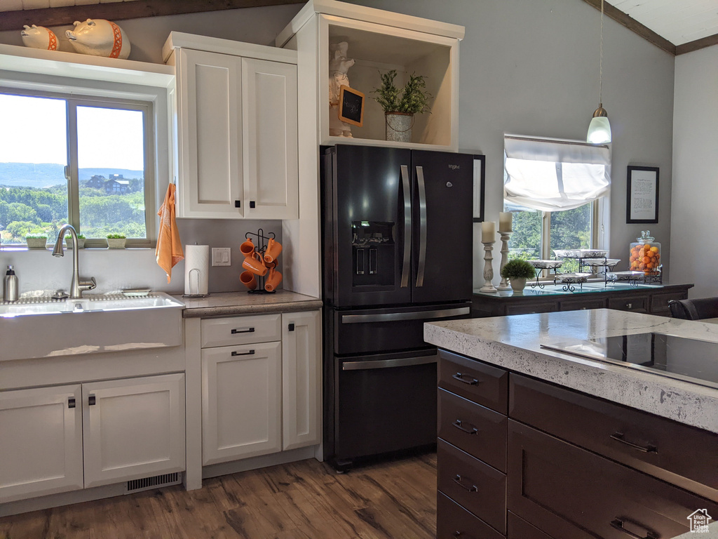 Kitchen featuring white cabinets, pendant lighting, black appliances, and a healthy amount of sunlight
