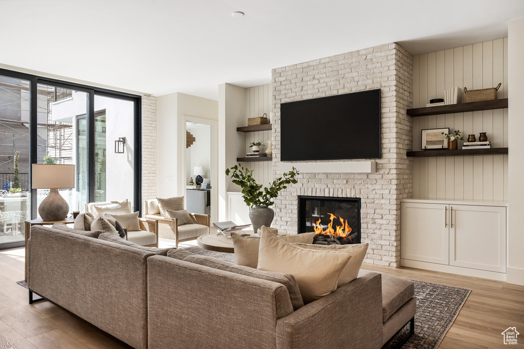 Living room featuring brick wall, a brick fireplace, and light hardwood / wood-style flooring