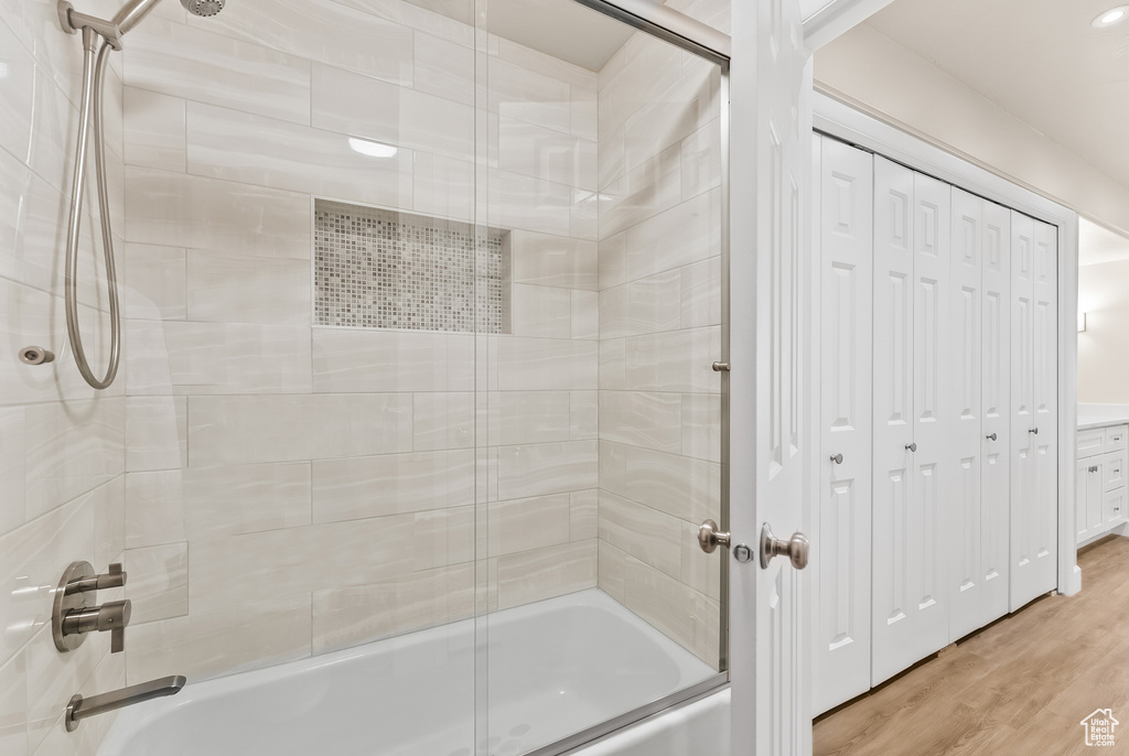 Bathroom with hardwood / wood-style floors and shower / bath combination with glass door
