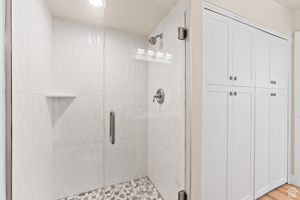Bathroom with wood-type flooring and a shower with shower door