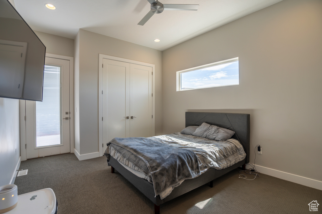 Bedroom featuring multiple windows, dark carpet, and ceiling fan