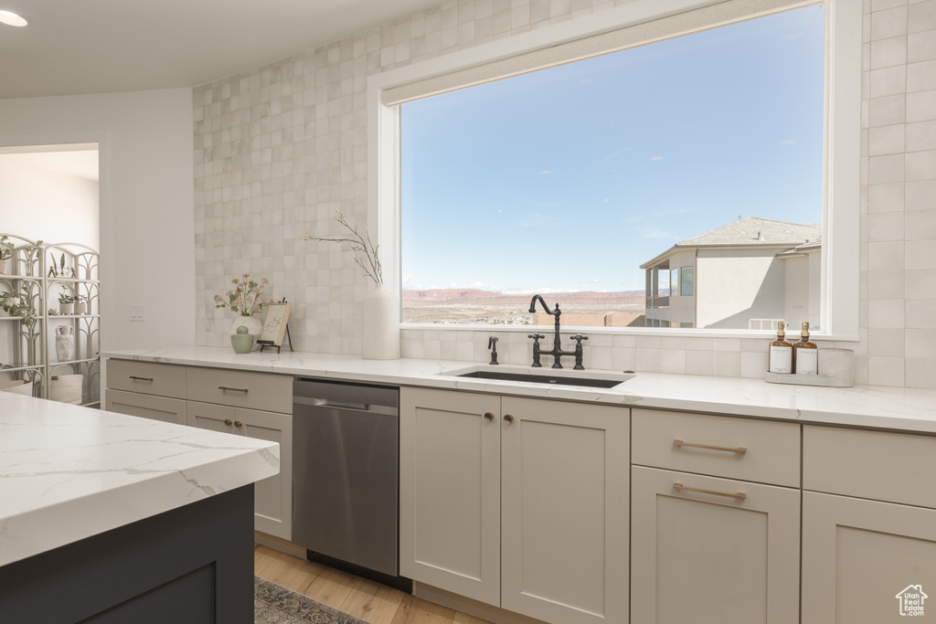Kitchen featuring sink, light hardwood / wood-style flooring, backsplash, and dishwasher