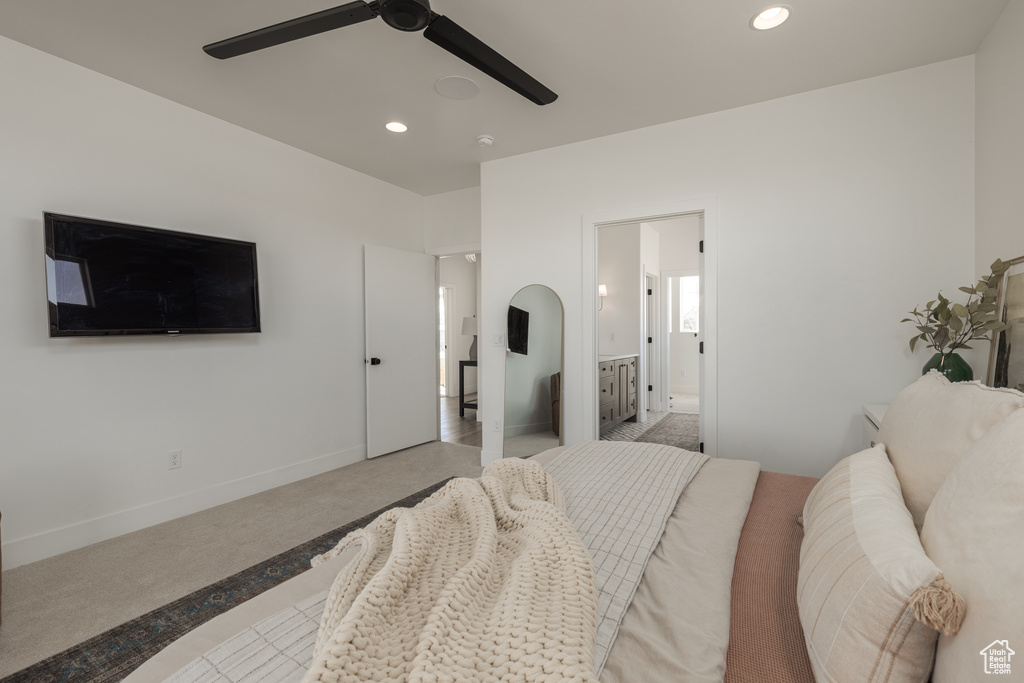 Carpeted bedroom with connected bathroom and ceiling fan