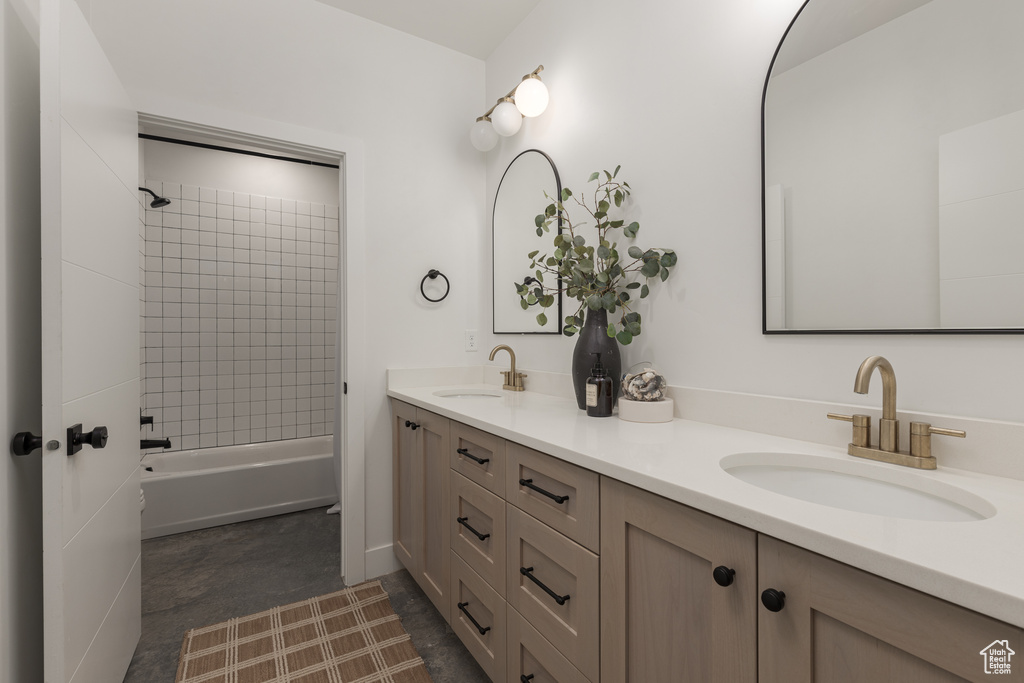 Bathroom featuring dual bowl vanity, tile floors, and tiled shower / bath