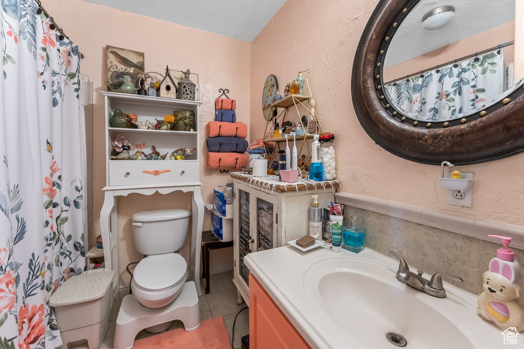 Bathroom with tile flooring, vanity with extensive cabinet space, and toilet