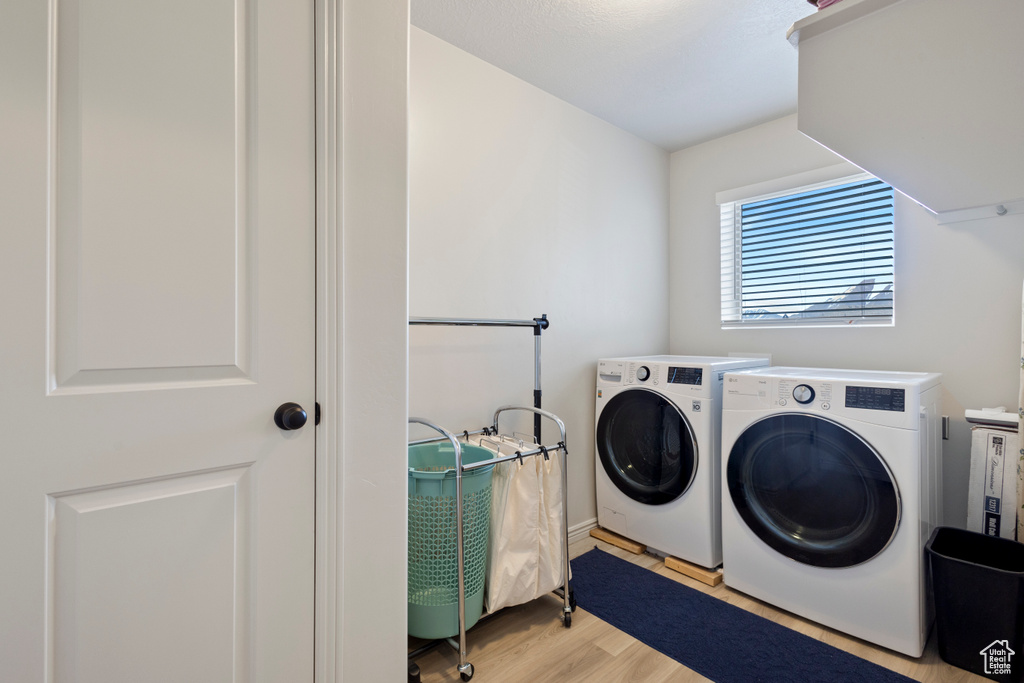 Laundry area featuring washing machine and dryer and light hardwood / wood-style floors