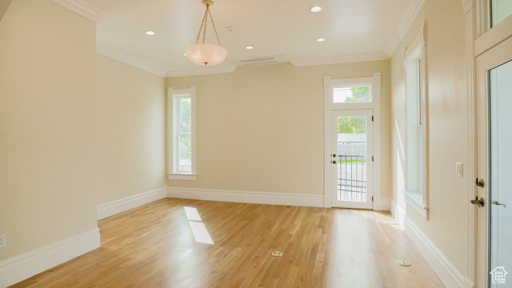 Unfurnished room with light hardwood / wood-style floors, ornamental molding, and a wealth of natural light