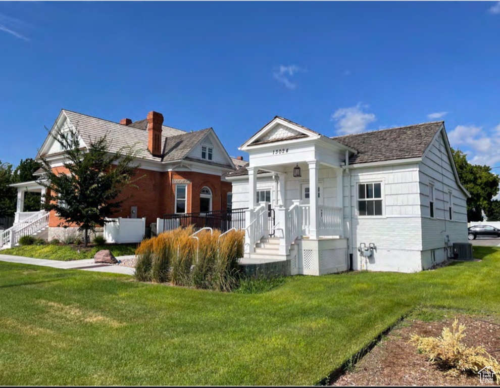 Rear view of house with a lawn, covered porch, and central AC