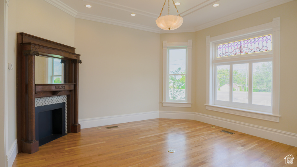 Unfurnished room with crown molding, light wood-type flooring, and a fireplace