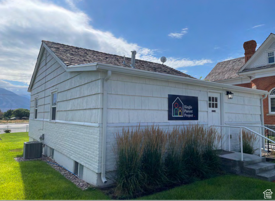 View of side of property with a lawn and central AC