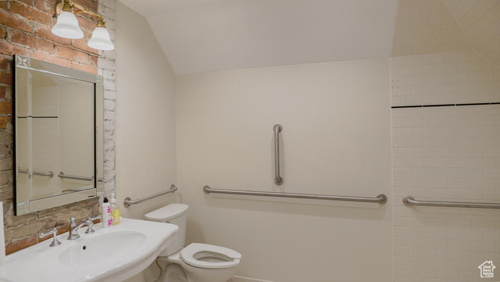 Bathroom with sink, vaulted ceiling, and toilet