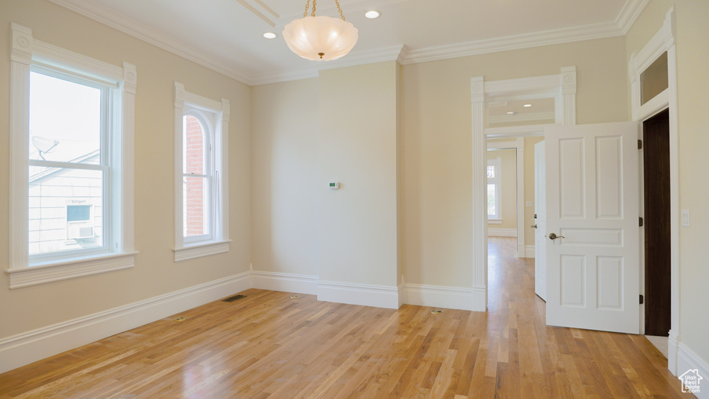 Spare room featuring crown molding and light hardwood / wood-style flooring