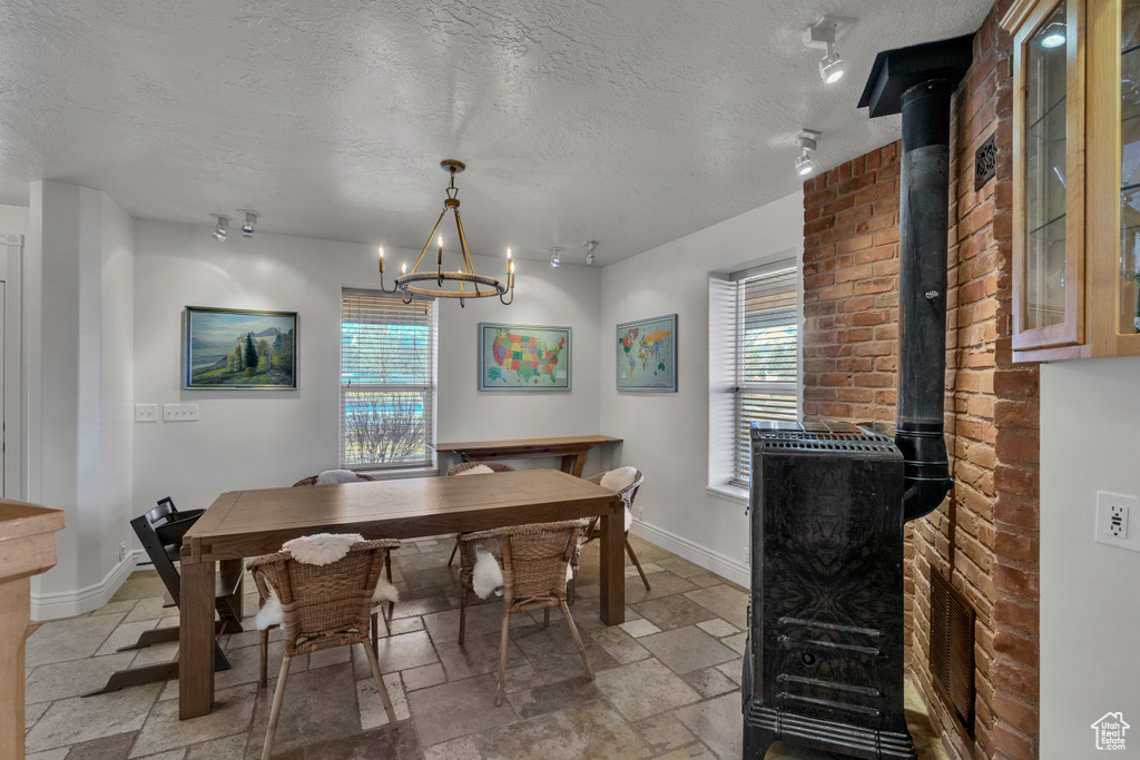 Dining area featuring light tile flooring, a wood stove, a wealth of natural light, and a chandelier