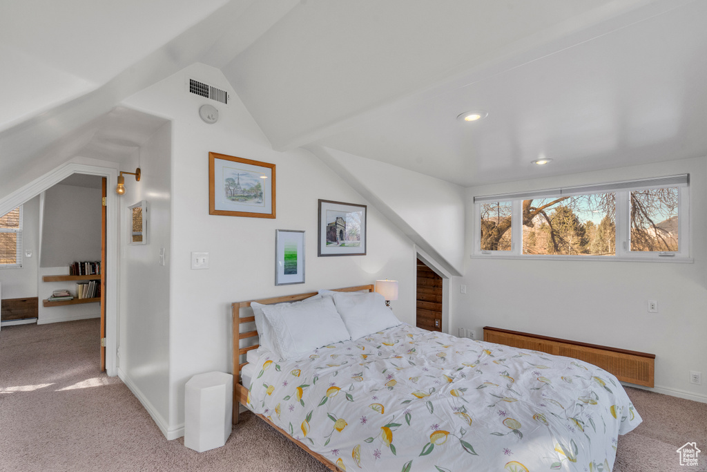 Carpeted bedroom featuring radiator heating unit and lofted ceiling