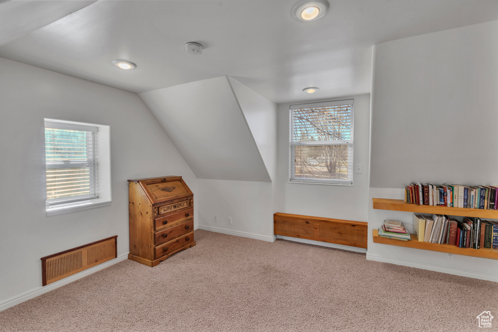 Bonus room with lofted ceiling and light colored carpet