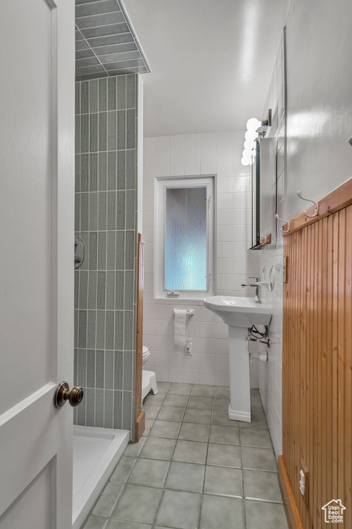 Bathroom featuring tile walls, tile floors, walk in shower, and toilet