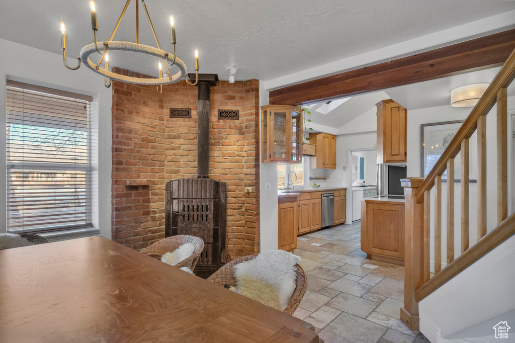 Tiled dining room with a wood stove, brick wall, a chandelier, and a healthy amount of sunlight