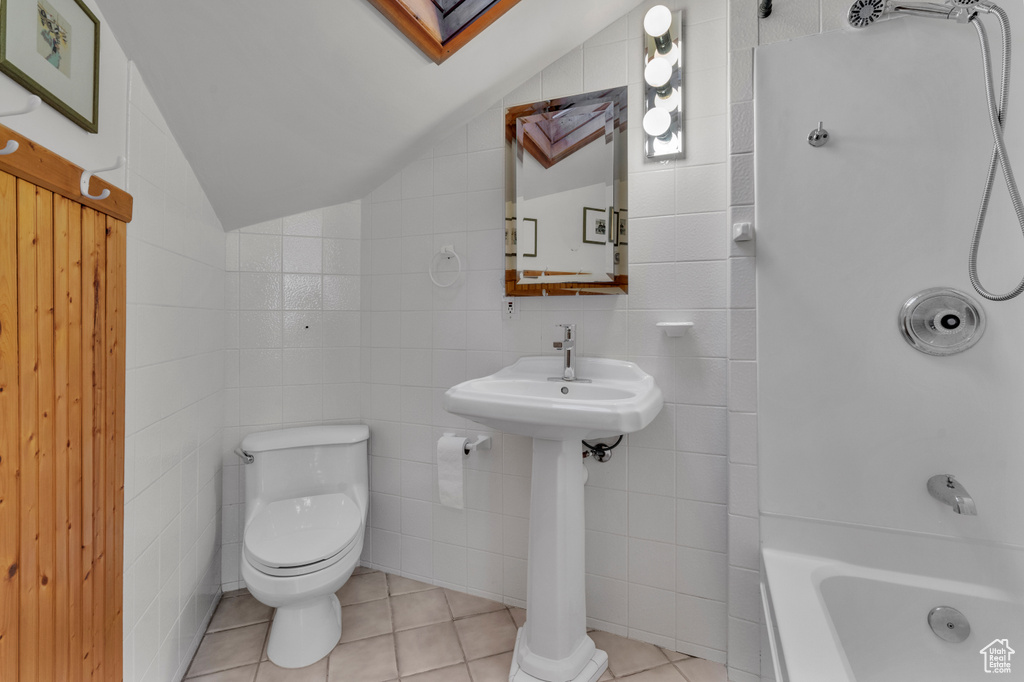 Bathroom with tile walls, tile floors, toilet, lofted ceiling, and  shower combination