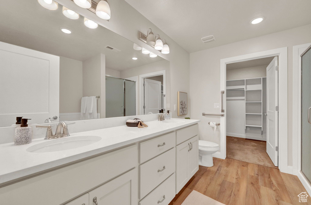 Bathroom featuring wood-type flooring, double sink, large vanity, and toilet