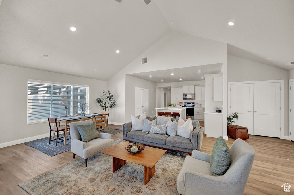 Living room featuring high vaulted ceiling, light wood-type flooring, and ceiling fan