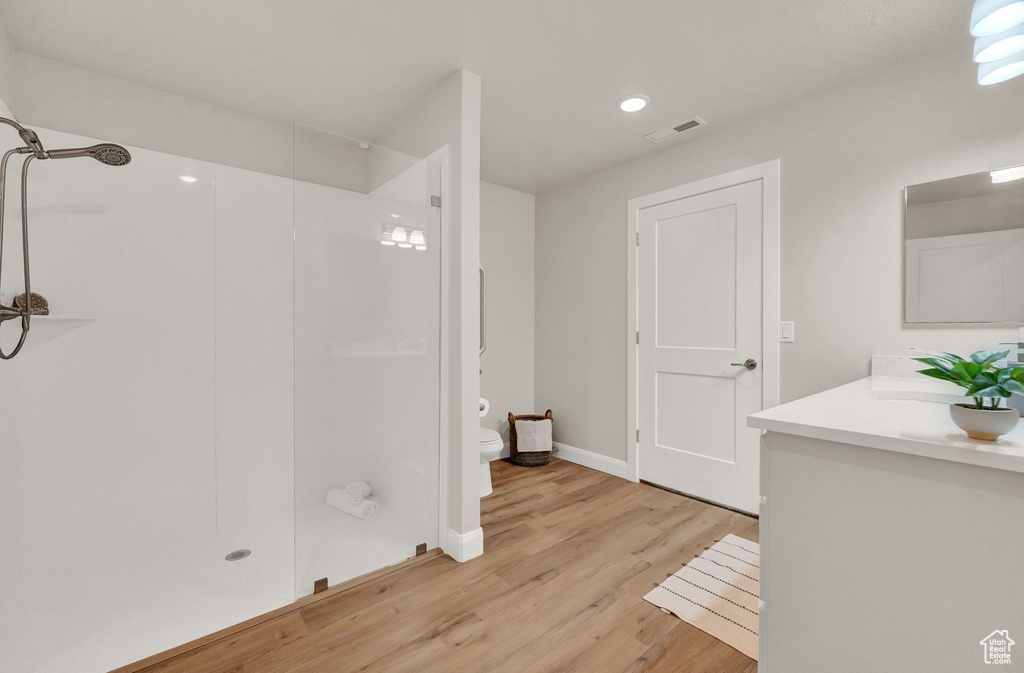 Bathroom featuring hardwood / wood-style floors, vanity, toilet, and a shower