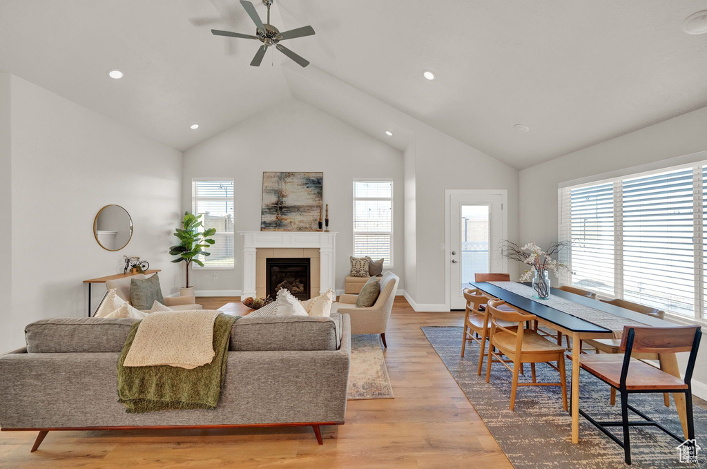 Living room featuring plenty of natural light, light wood-type flooring, high vaulted ceiling, and ceiling fan