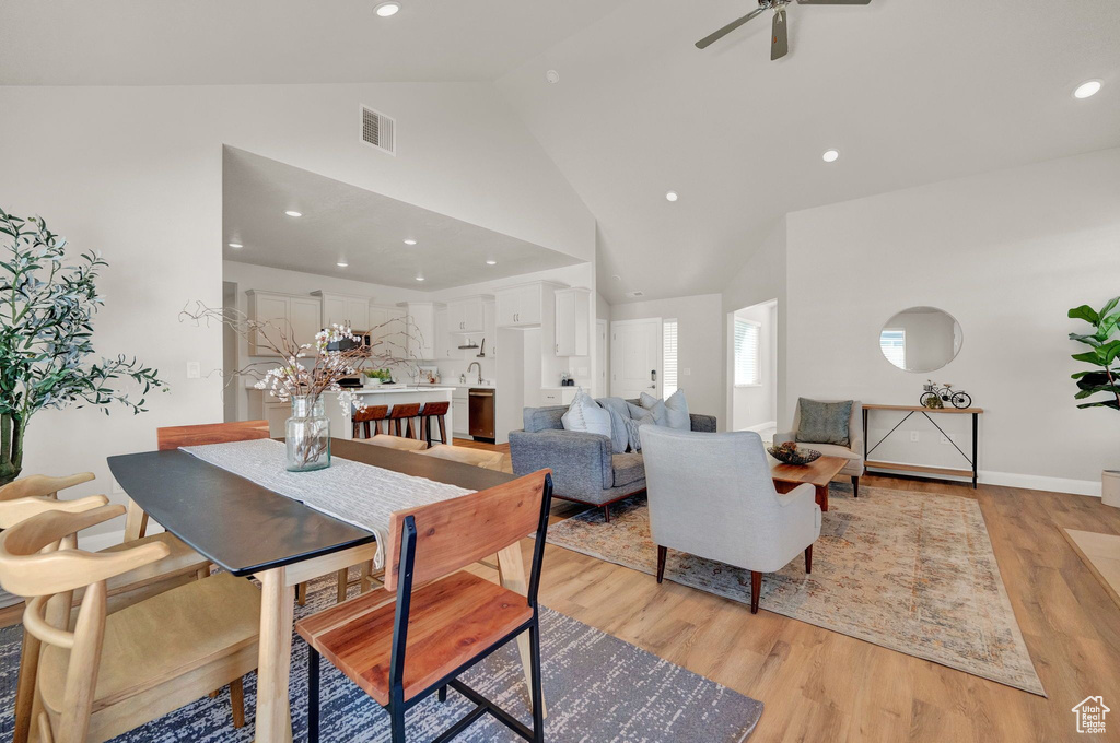 Dining space with ceiling fan, light hardwood / wood-style flooring, and high vaulted ceiling