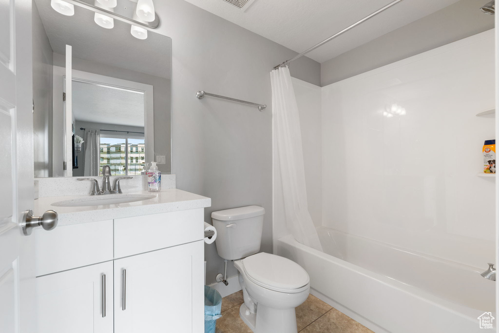 Full bathroom with tile flooring, shower / bath combination with curtain, vanity, and toilet