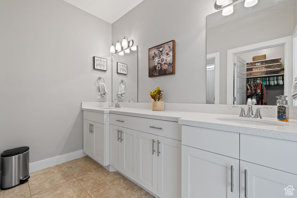 Bathroom featuring double sink, tile flooring, and vanity with extensive cabinet space