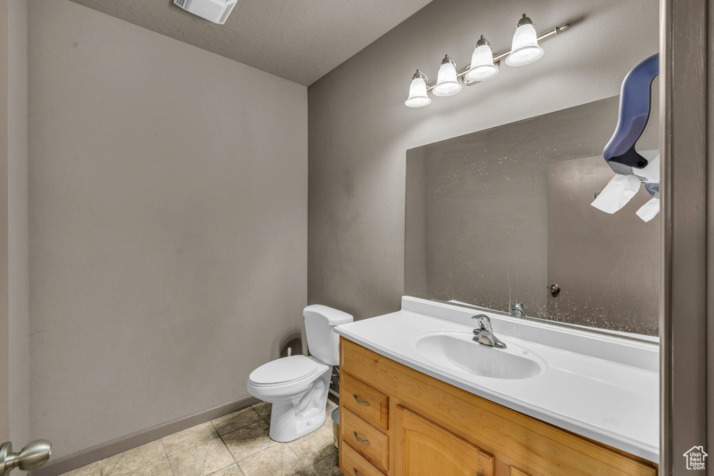Bathroom with tile floors, vanity, toilet, and a textured ceiling