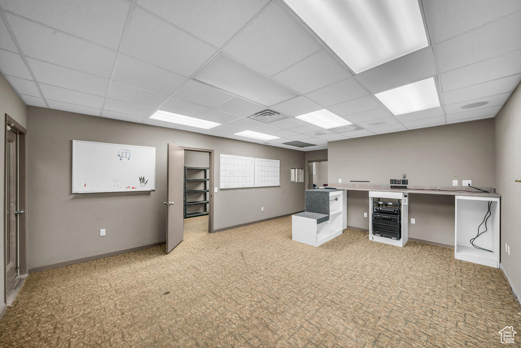 Unfurnished office with wine cooler, a drop ceiling, and light colored carpet