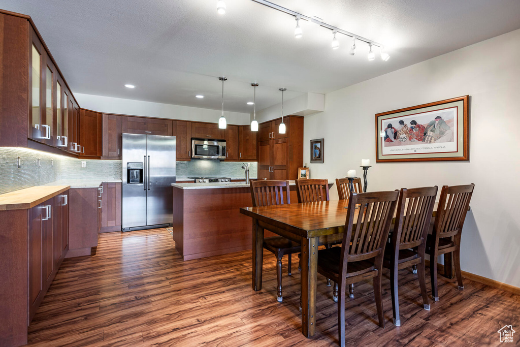 Dining room with dark hardwood / wood-style flooring and rail lighting