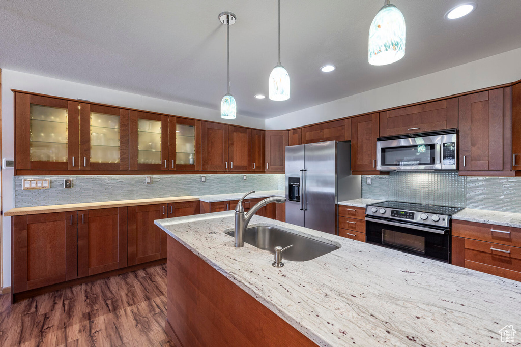 Kitchen featuring appliances with stainless steel finishes, sink, decorative light fixtures, and dark hardwood / wood-style floors