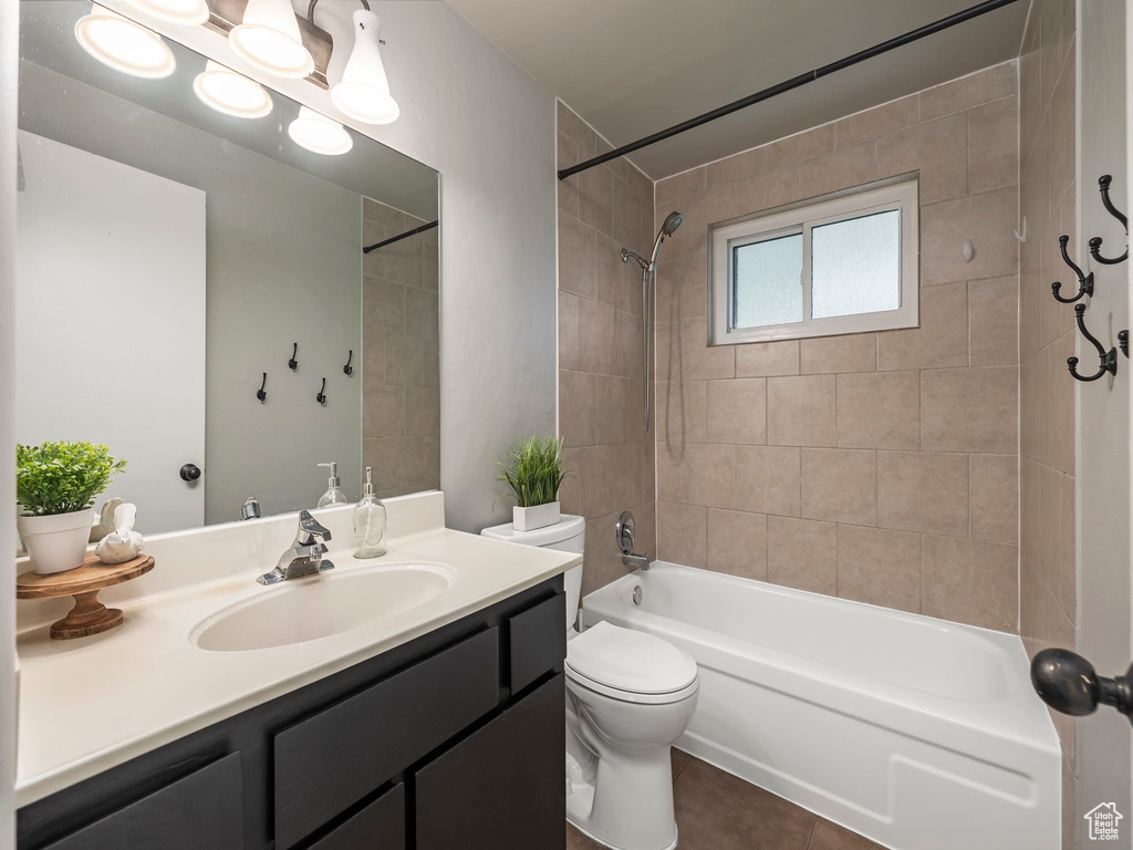 Full bathroom featuring tile floors, large vanity, toilet, and tiled shower / bath combo