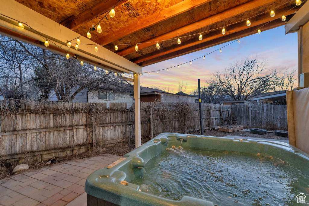 Patio terrace at dusk featuring a hot tub