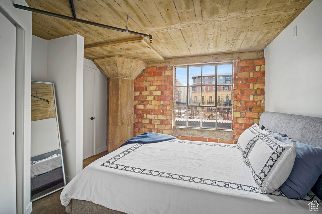 Bedroom with wooden ceiling and brick wall